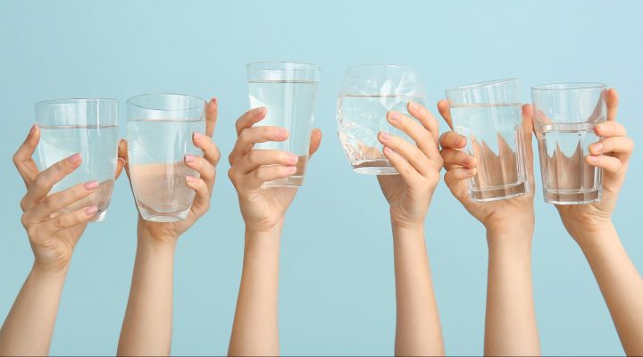 hands holding water glasses