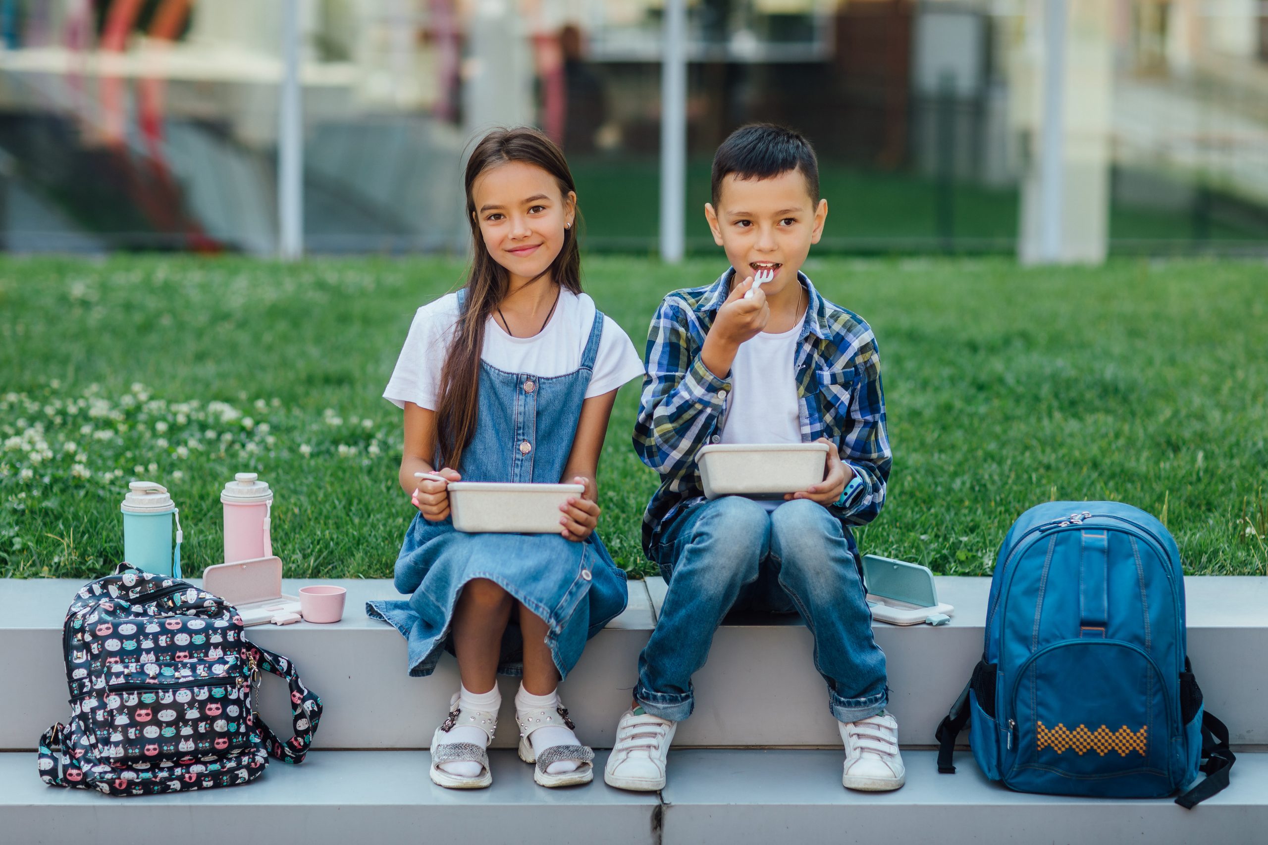 two school children eating a lunch outside