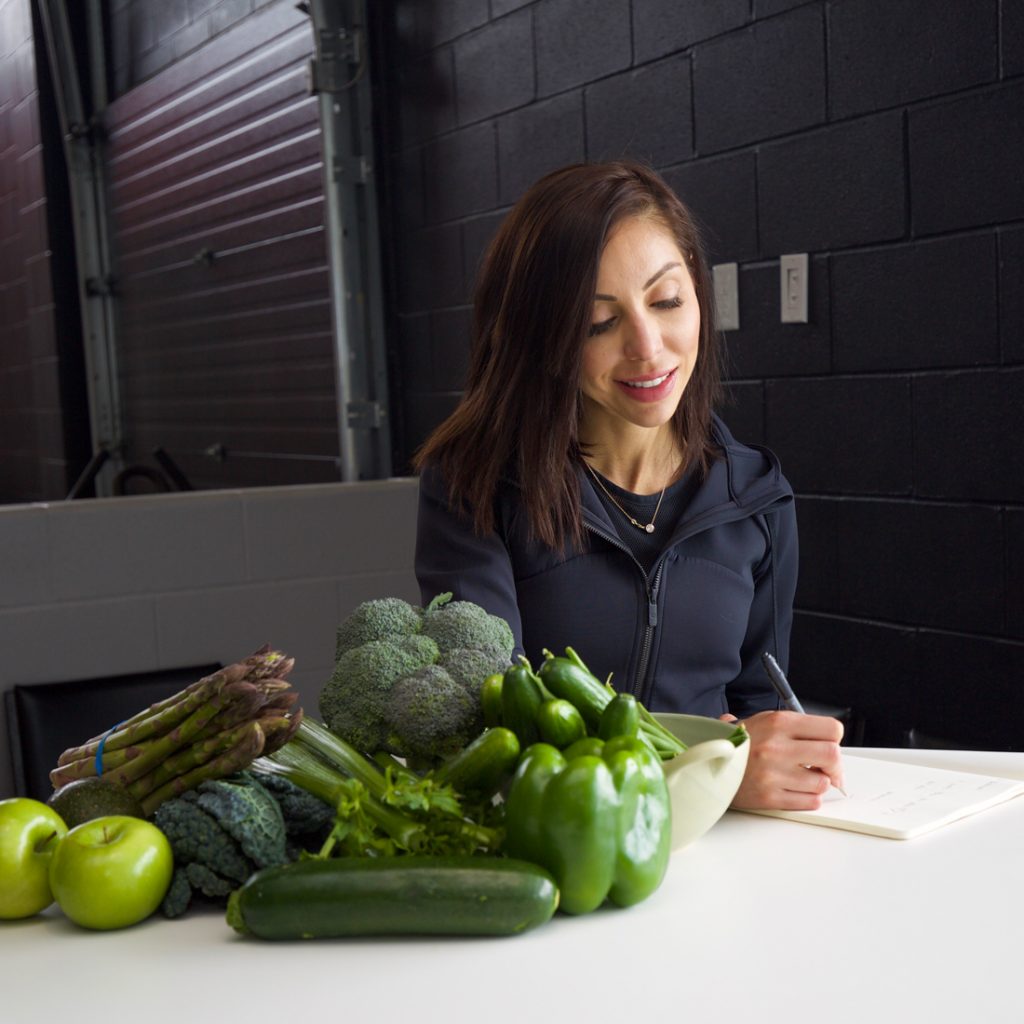 An image of Lisa Spriet planning sports nutrition for a client. Picture includes green vegetables on the table