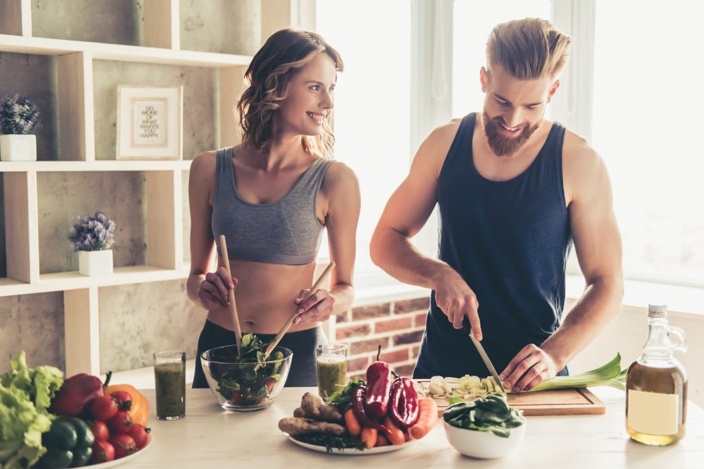A fit couple following a couples nutrition program and making a meal together.