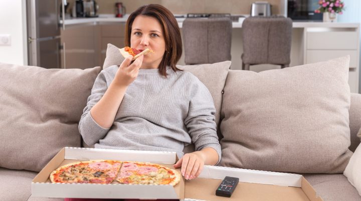 women on emotionally eating pizza and watching tv