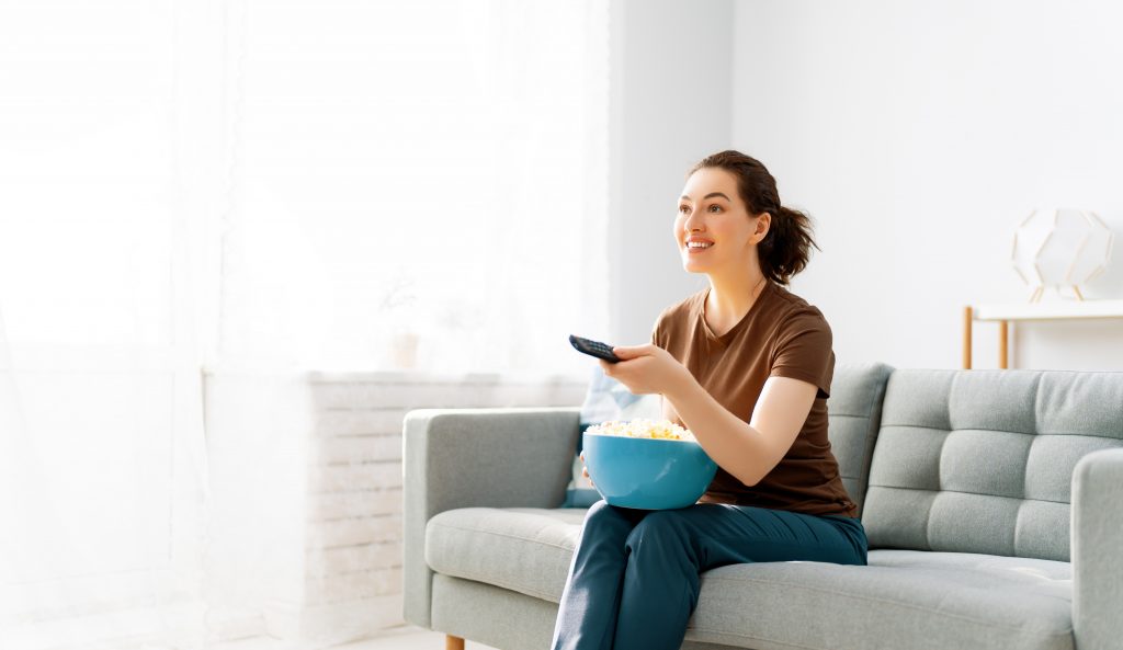 Young woman watching  TV and eating popcorn