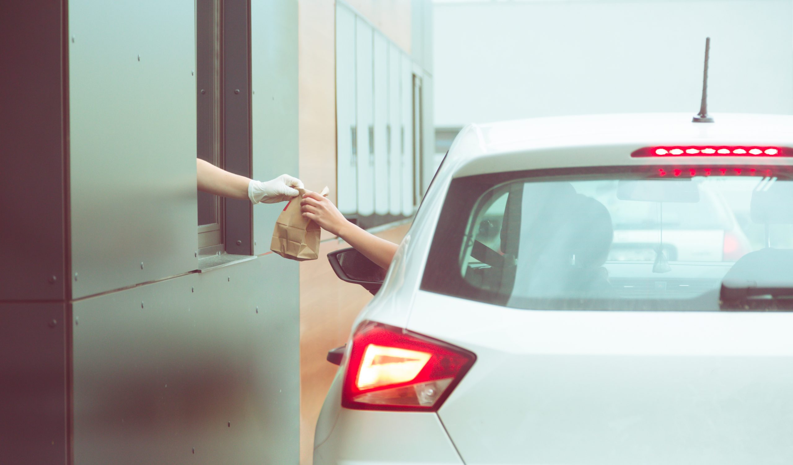A person receiving a bag of food through a drive-through window